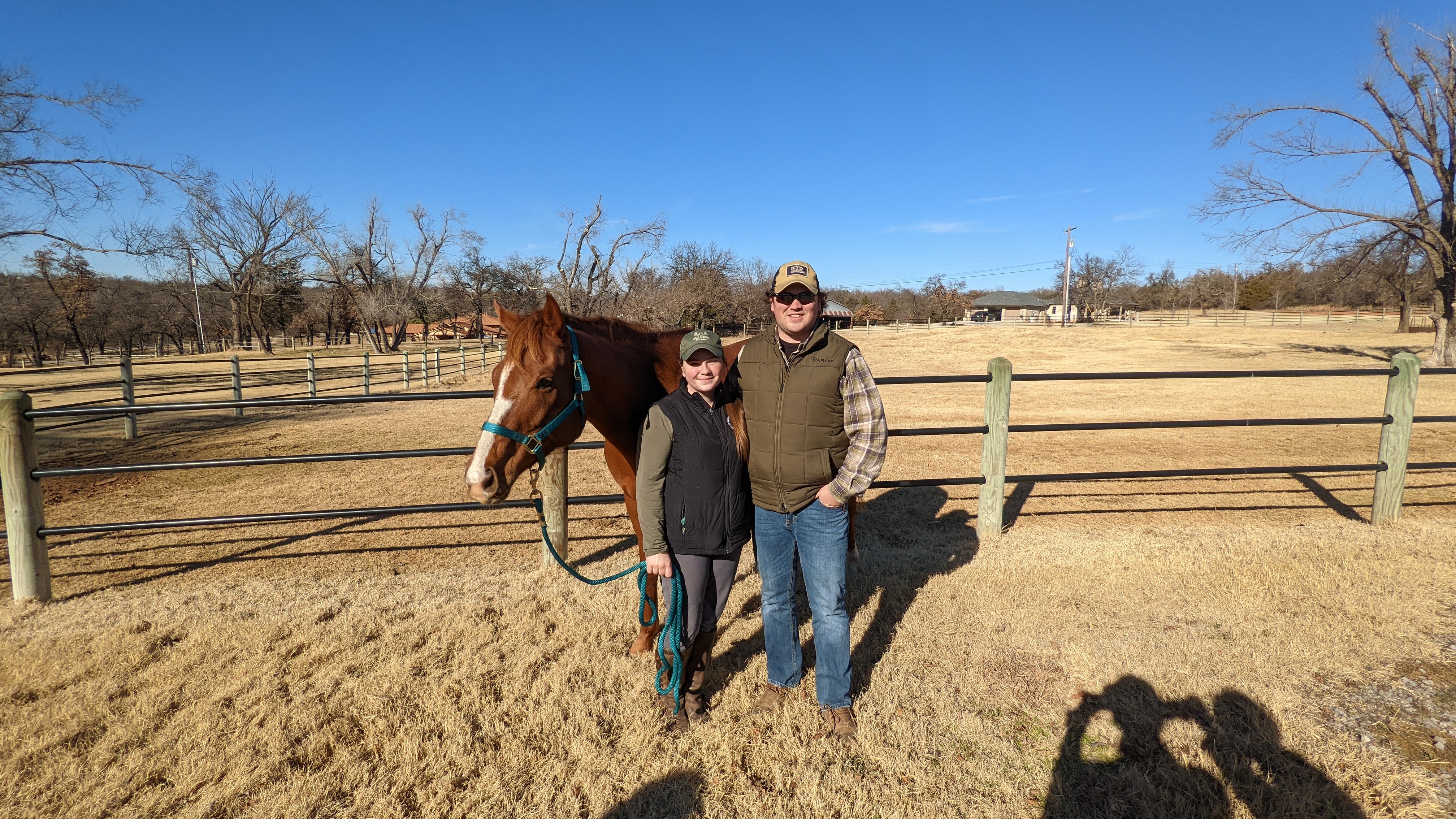 EqTek founders Lucy and Tyler with a chestnut horse in an Oklahoma pasture